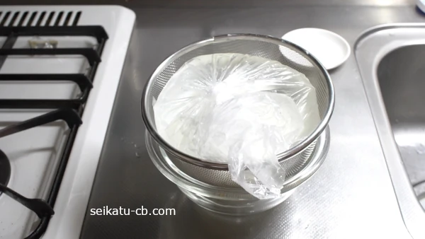 キッチンペーパーで包んだ塩麹ヨーグルトの上に重しをのせる